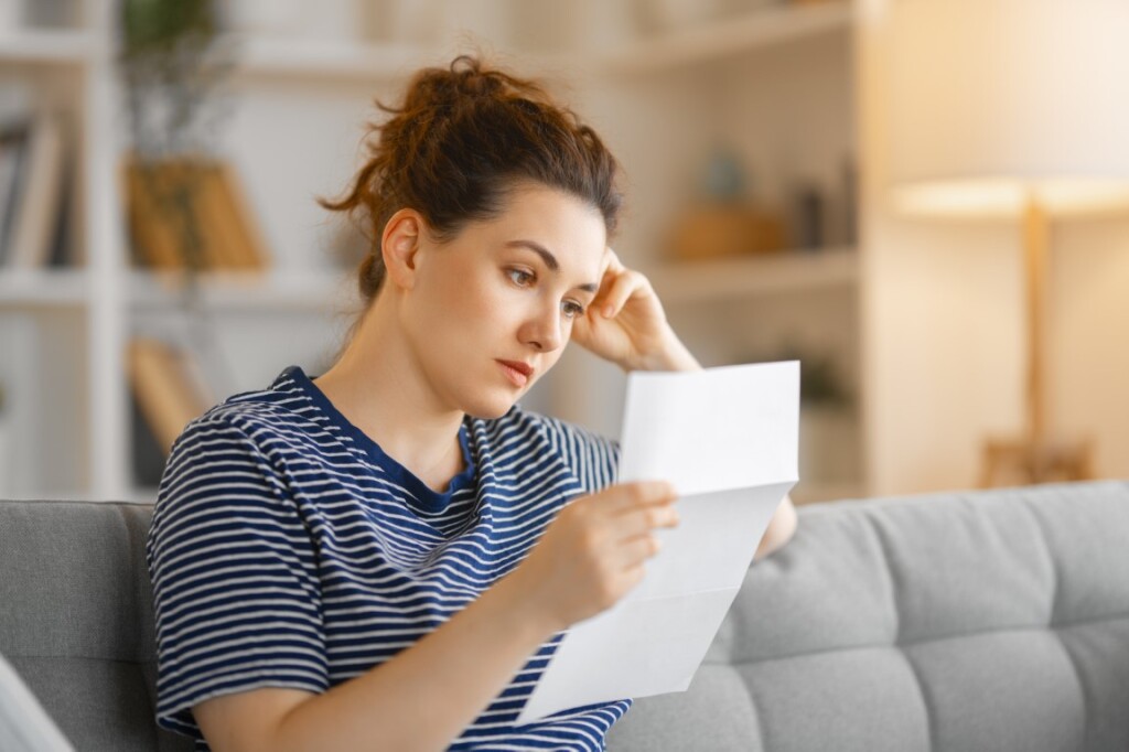 Woman, sitting on the sofa with a paper receipt